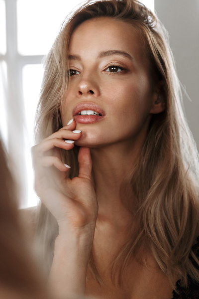 Woman with long hair touching her face.